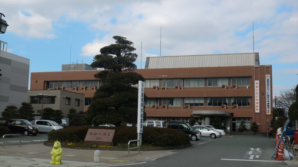 熊本県御船町役場の庁舎。3階建ての建物の前に松の木と駐車場