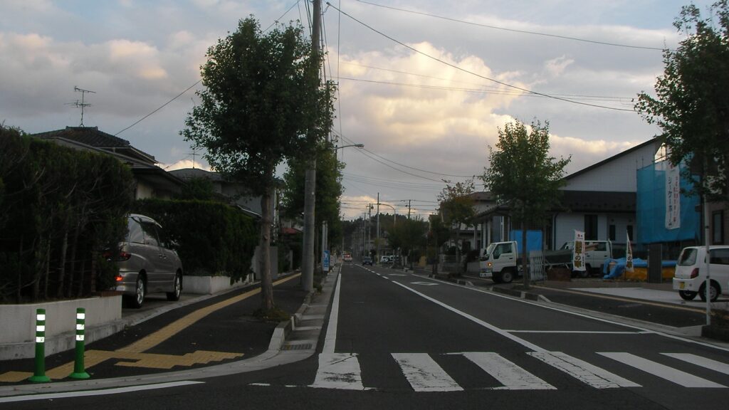 あけの平一〜二丁目の街並み。街路樹の並ぶ道と住宅、商店が続く