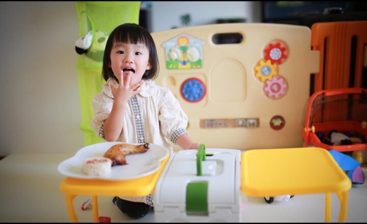 保育室で知育玩具に囲まれておやつを食べる幼い子ども