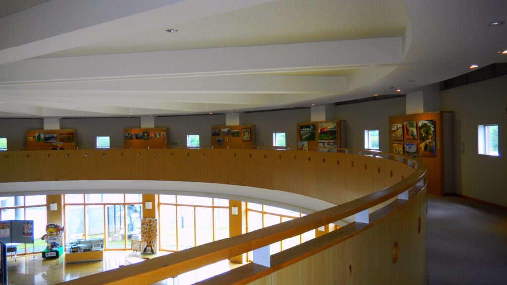 富谷市民交流ホールの回廊。曲面の手すりに沿って展示のモニターが並ぶ