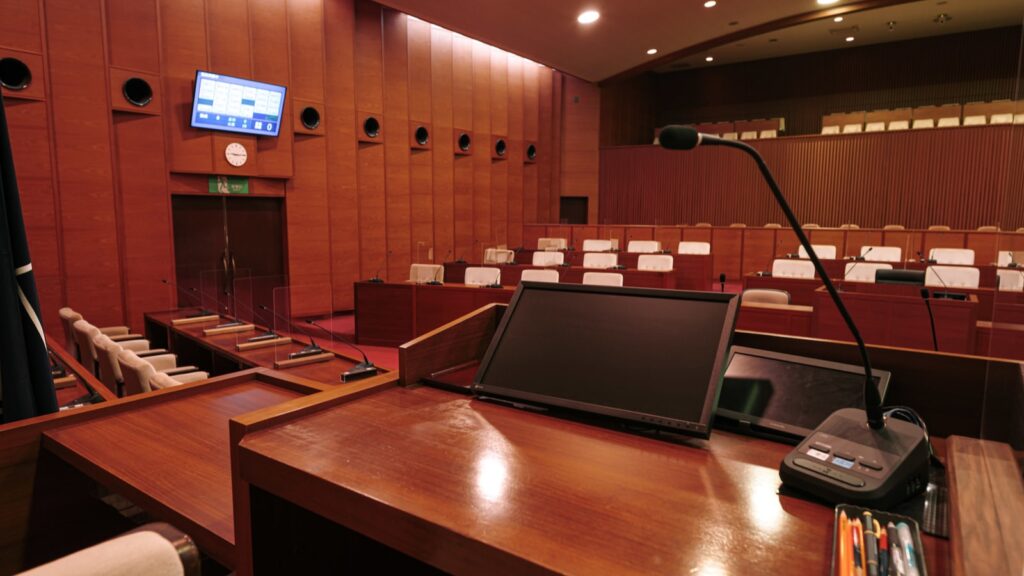 津山市議会の議場にある演壇マイク、議席、電子表決システムのモニター