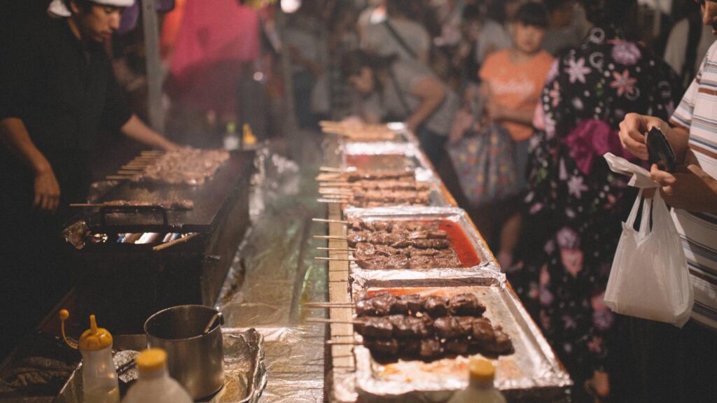 夜祭りの屋台で串焼きを買う人たち