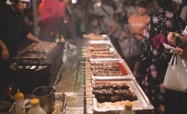 夜祭りの屋台で串焼きを買う人たち