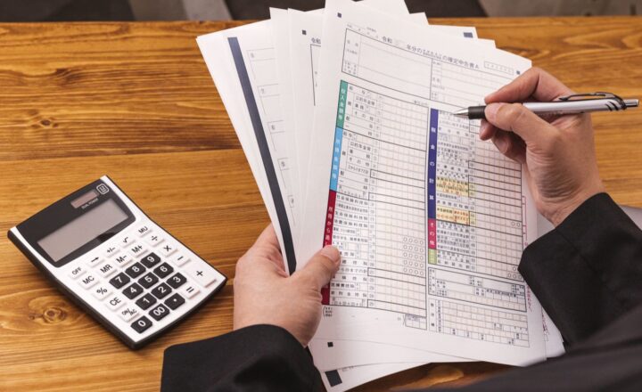 税の書類を手に電卓で金額を確認する人