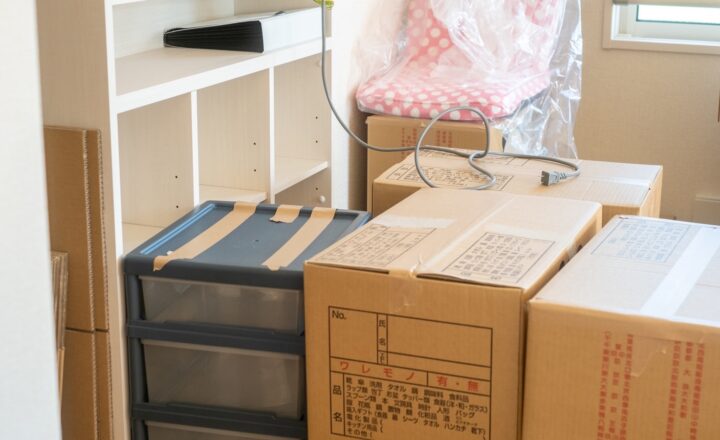 引っ越し前の室内に積み重ねられた段ボール箱と家具