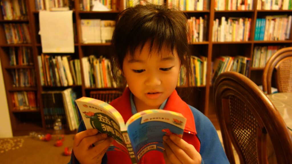 本棚の前で本を読む子どもの関連イメージ写真