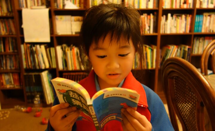 本棚の前で本を読む子どもの関連イメージ写真
