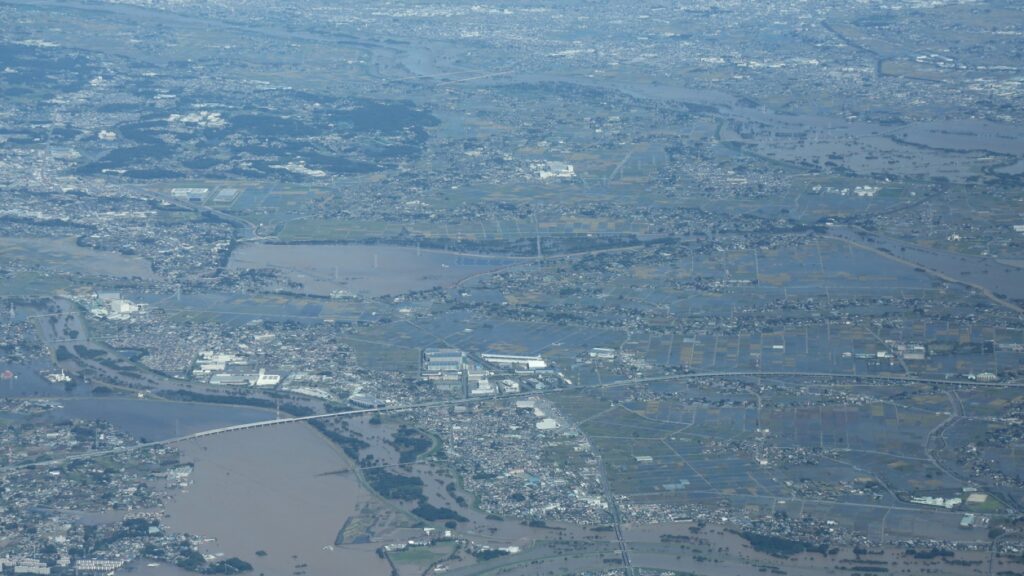 令和元年東日本台風の翌日に撮影された空中写真。住宅地と水田が広く濁った水に覆われ、道路や橋が水没している